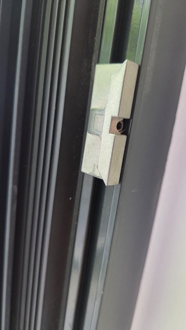 Nahaufnahme eines Fenster- oder Türschlosses am Rahmen mit sichtbarem Zylinderschloss.