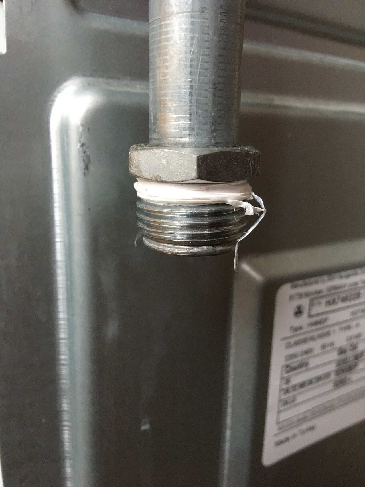 Nahaufnahme eines Metallrohrs mit Gewinde, Weißes Teflonband um die Verschraubung.