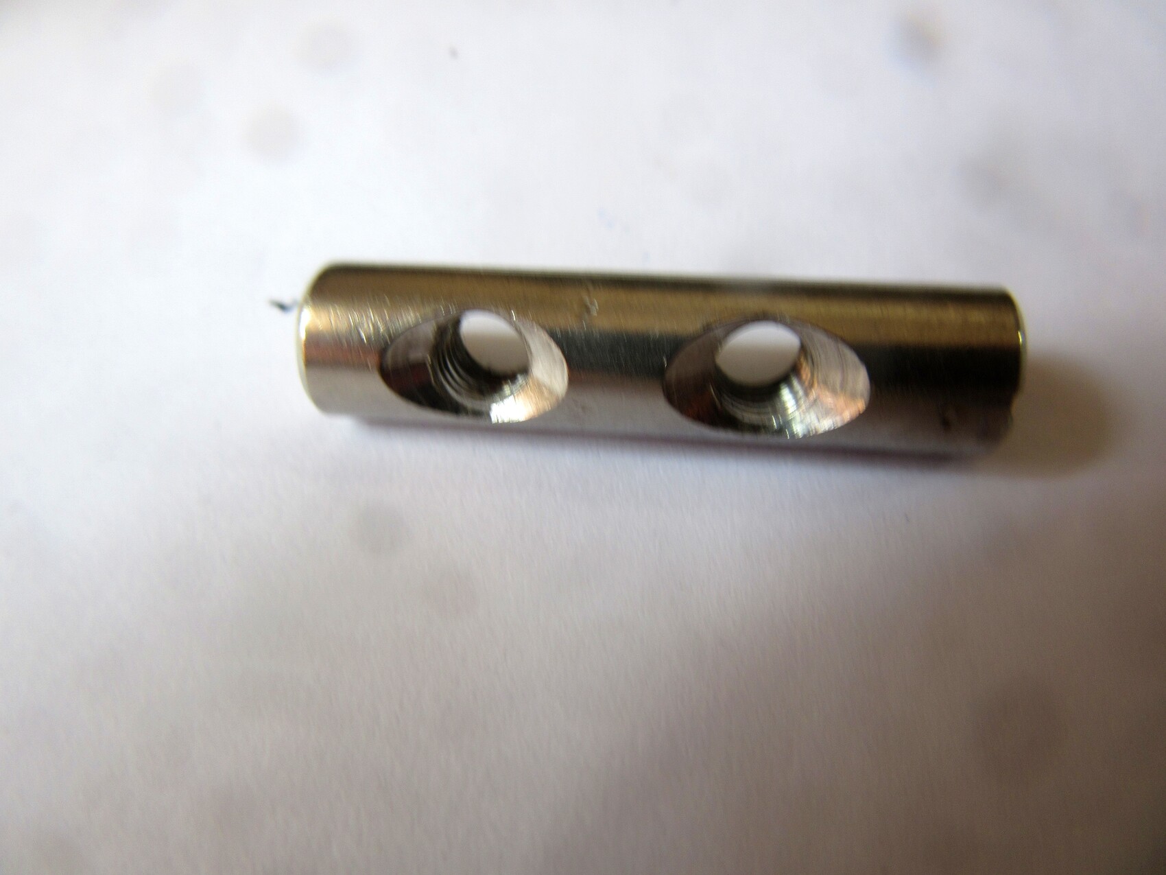 Glänzendes Metallrohr mit zwei runden Öffnungen und Innengewinden.