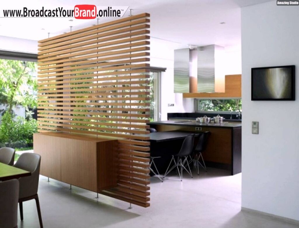 Moderne Küche mit Holz-Lamellen-Raumteiler, Esstisch links, Kücheninsel und TV an der Wand.