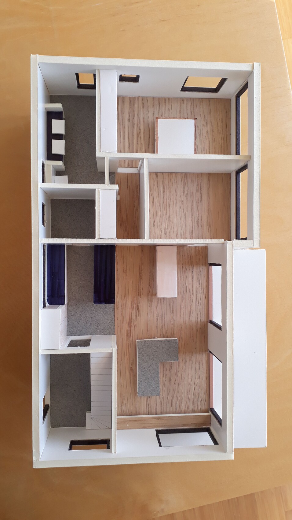 Modell eines Haus-Grundrisses von oben: Räume, Treppe, Holzboden und Fenster.