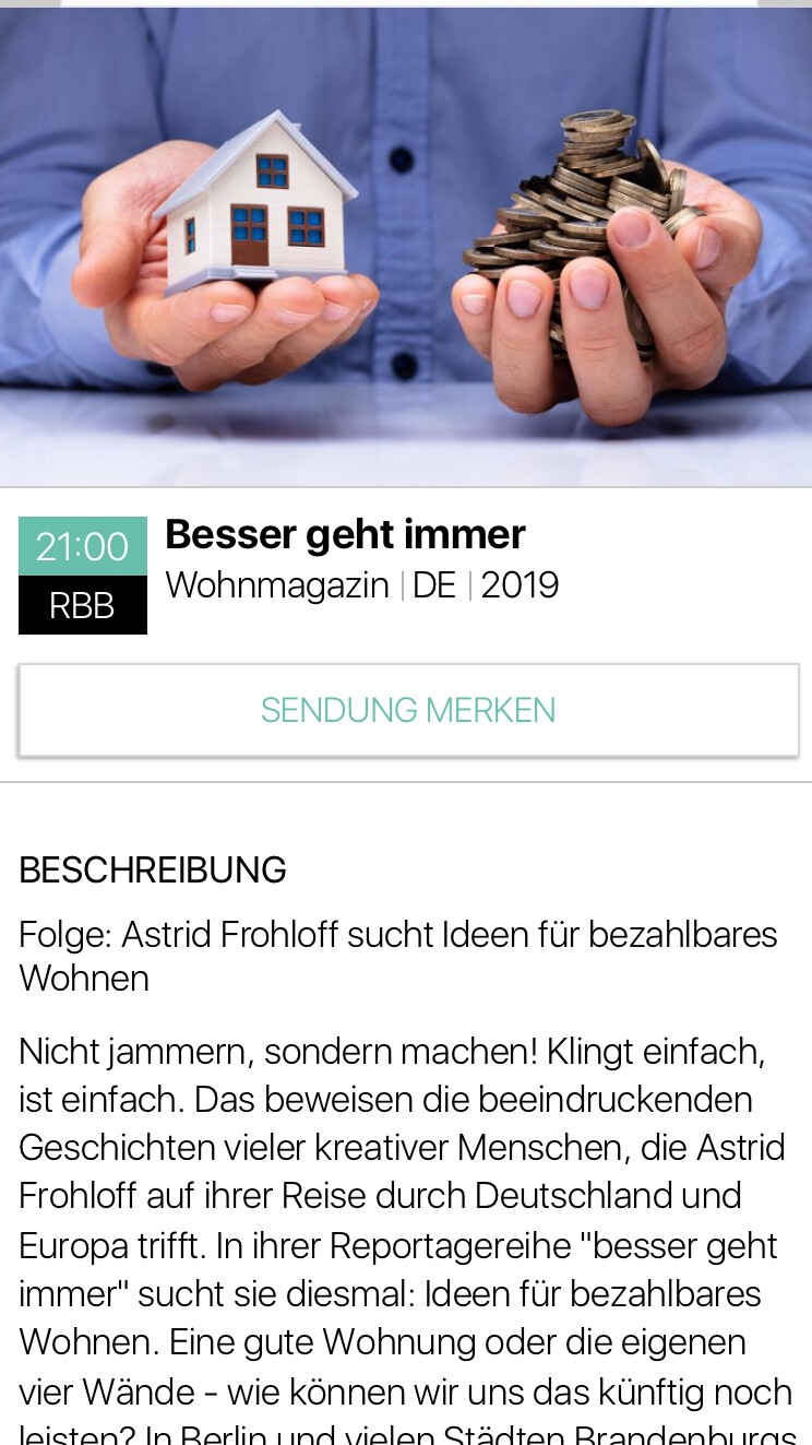 Modellhaus in einer Hand neben Münzstapel als Symbol für Baufinanzierung