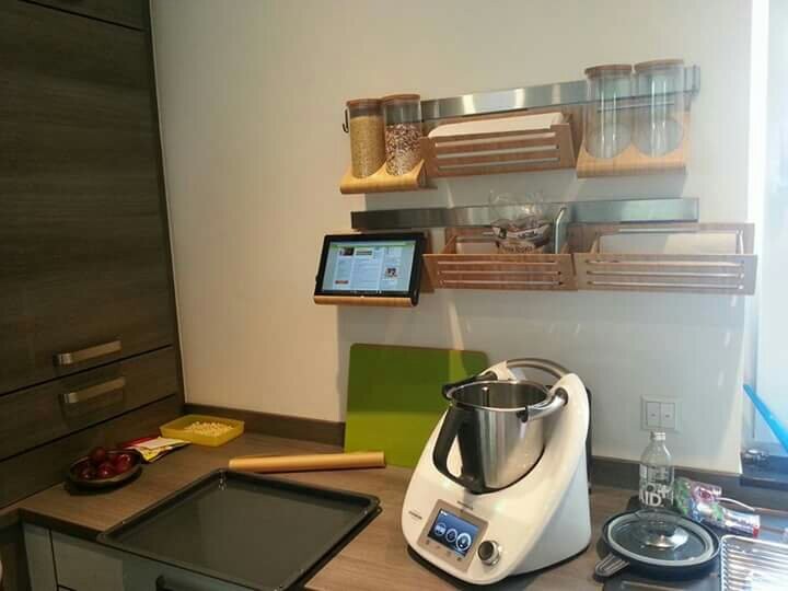 Küchenarbeitsplatte mit Thermomix-Multikocher, Holzregale mit Gläsern und Vorräten.