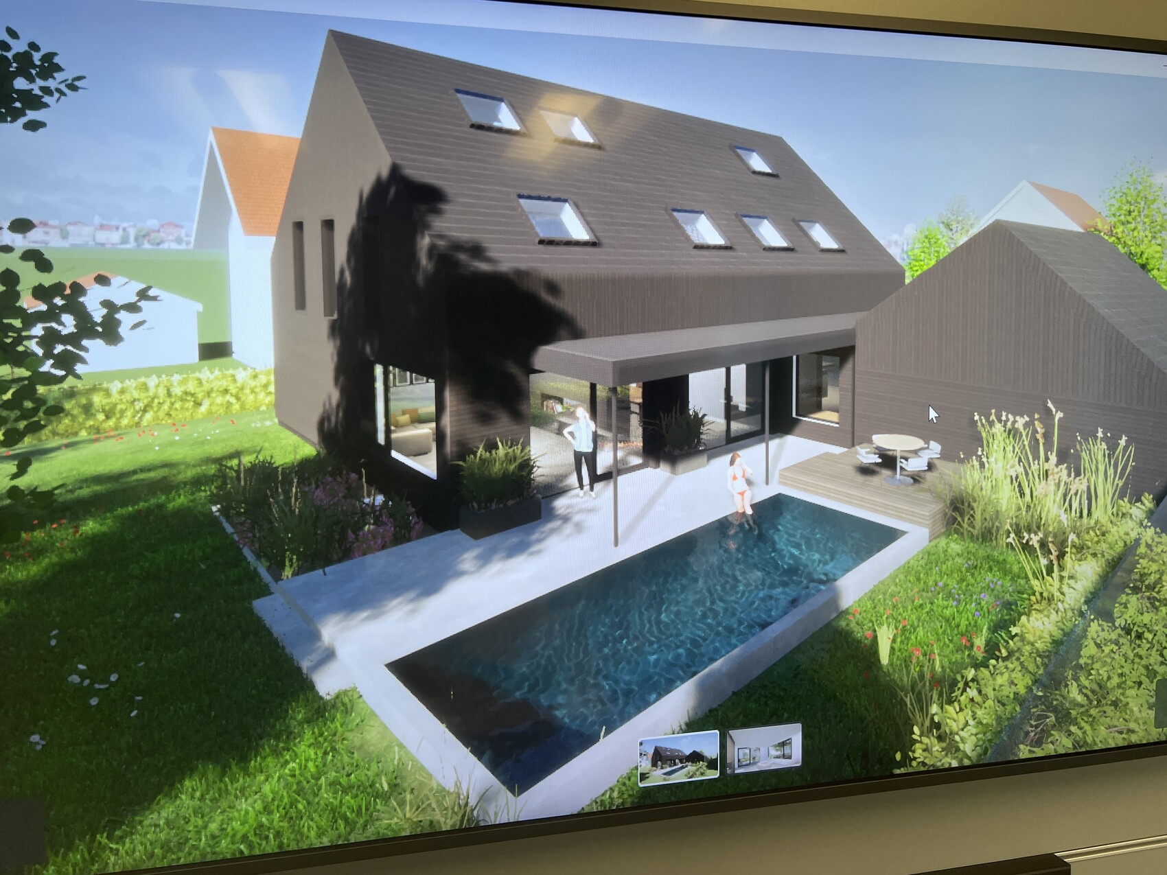 Modernes braunes Haus mit schrägem Dach, Dachfenstern, einem Pool, Holzdeck und zwei Personen am Pool.
