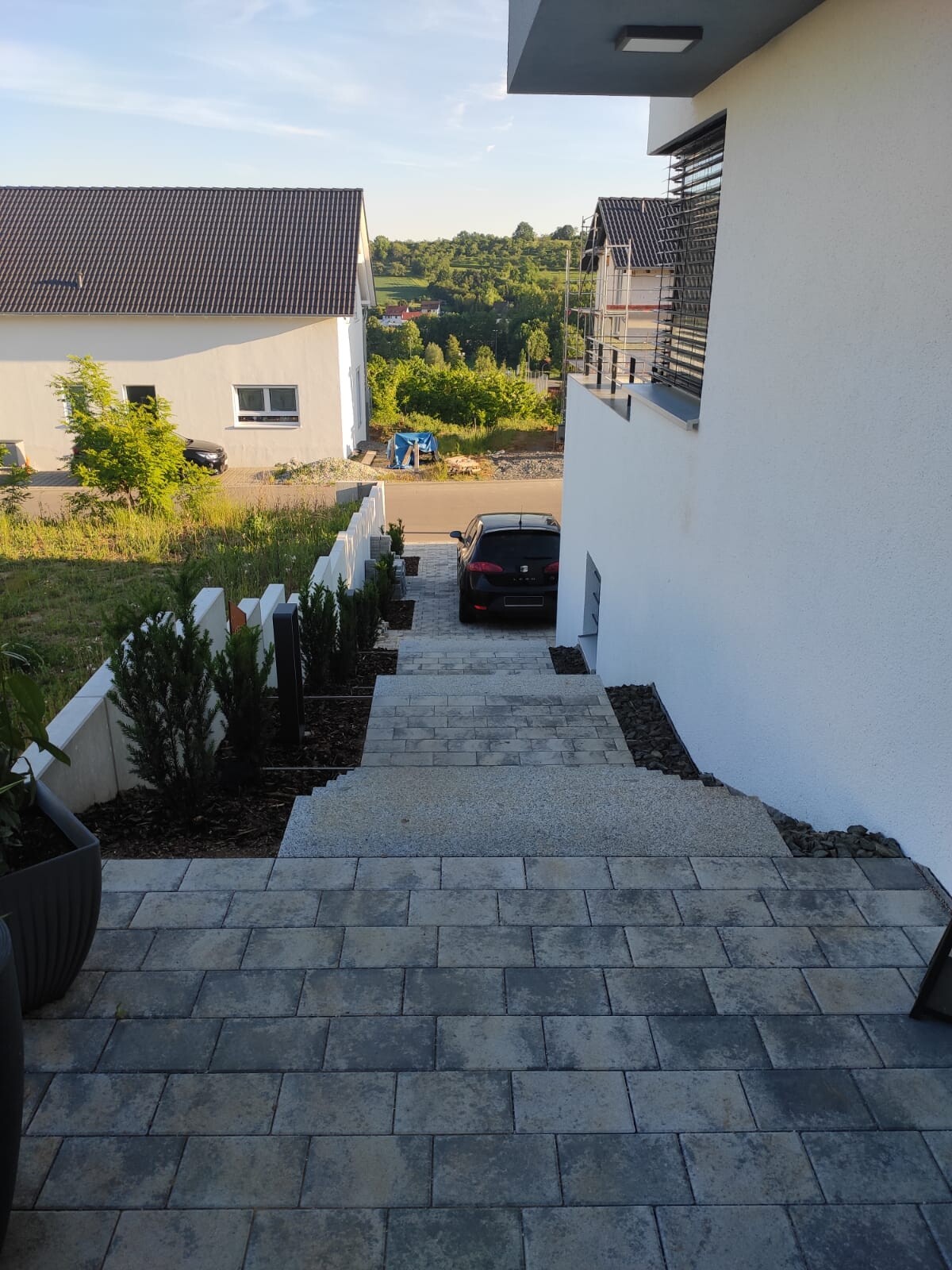 Blick von der Treppe zu einem geparkten schwarzen Auto vor modernem Gebäude
