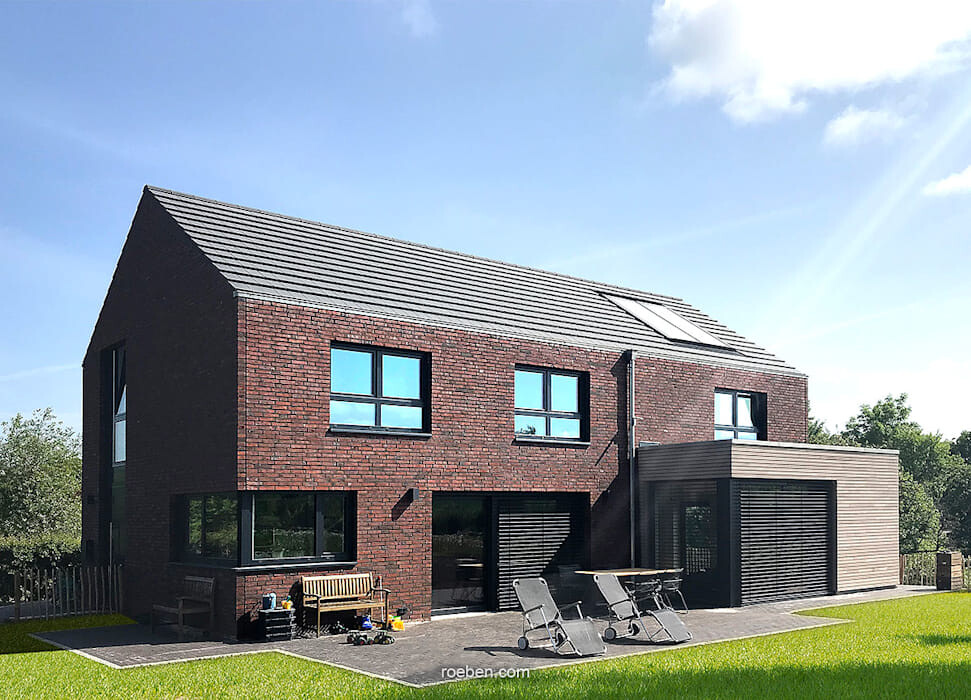 Moderne zweistöckige Backsteinvilla mit Terrasse, Solarpanel am Dach und Gartenmöbeln