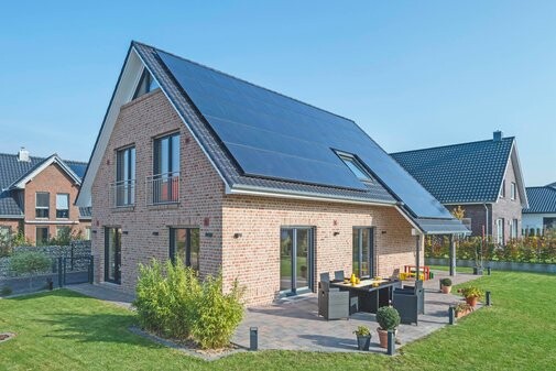 Einfamilienhaus aus Backstein mit Solarpanelen auf dem Dach, Terrasse und Garten.