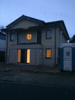 Moderne Backstein-Hausfront bei Dämmerlicht mit beleuchteten Fenstern