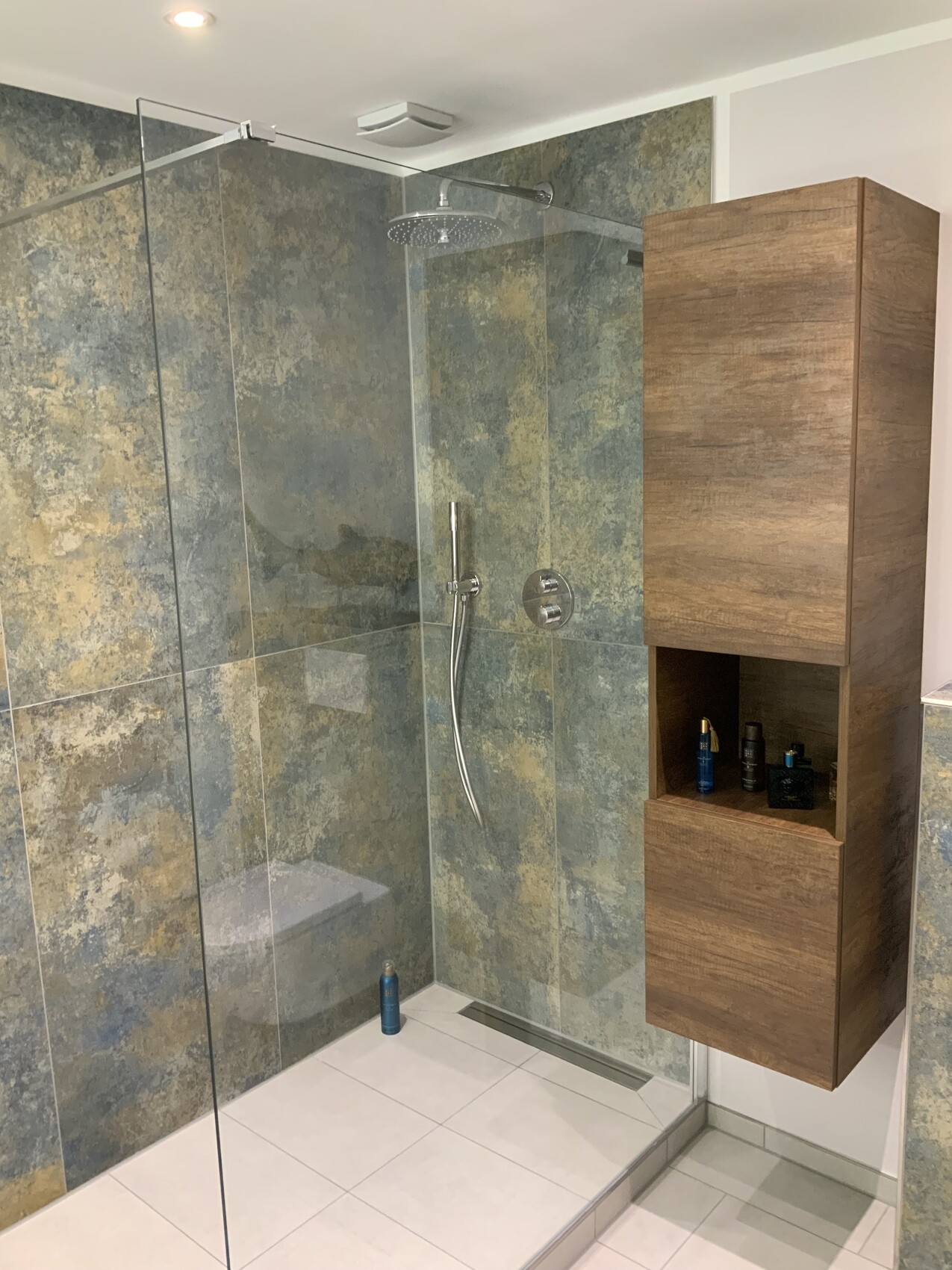Moderne Dusche: Glaswand, Regen-Dusche, Handbrause, Holzschrank mit Pflegeprodukten.