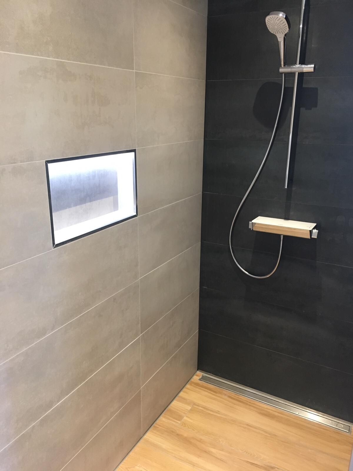 Moderne Dusche: hellgraue und schwarze Fliesen, Nische, Handbrause, Holzablage
