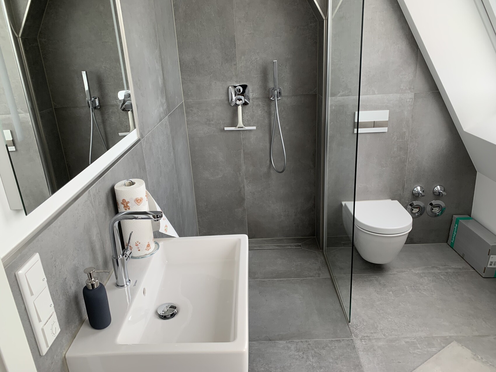 Modernes Badezimmer: graue Fliesen Waschbecken mit Armatur Seifenspender Toilette Dusche mit Glas
