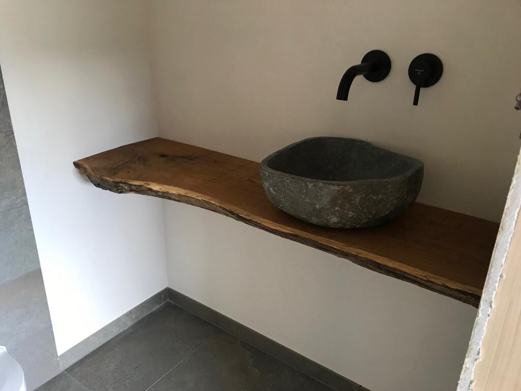 Naturholz-Live-Edge-Tisch mit dunklem Stein-Waschbecken und schwarzen Wandarmaturen