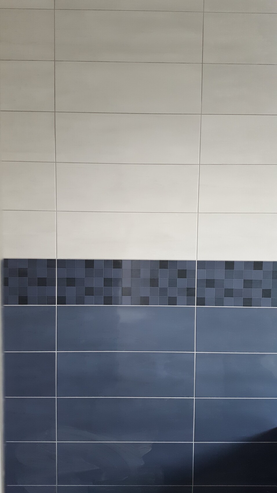 hellgraue Großfliesen oben, dunkle Pixel-Mosaikleiste, darunter dunkelblaue Großfliesen.