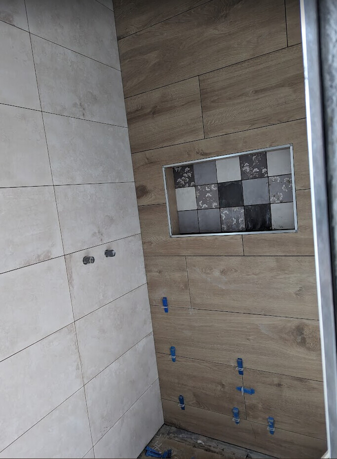 Badezimmerwand mit Holzoptik-Tonfliesen, Nische mit gemusterten Fliesen und blauen Clips.