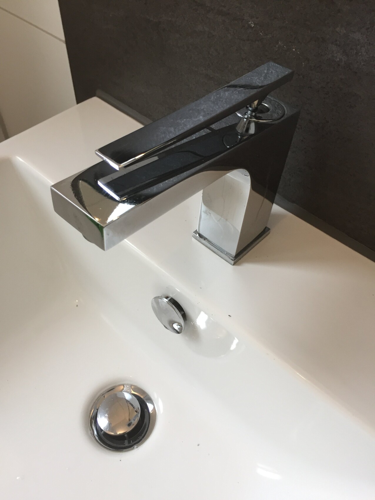 Moderne chromierte Badarmatur über weißem Waschtisch im Badezimmer.