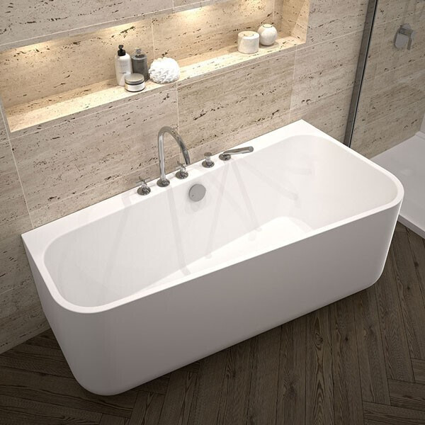 Freistehende weiße Badewanne mit Armaturen, Holzboden und Steinwandregal mit Pflegeprodukten.