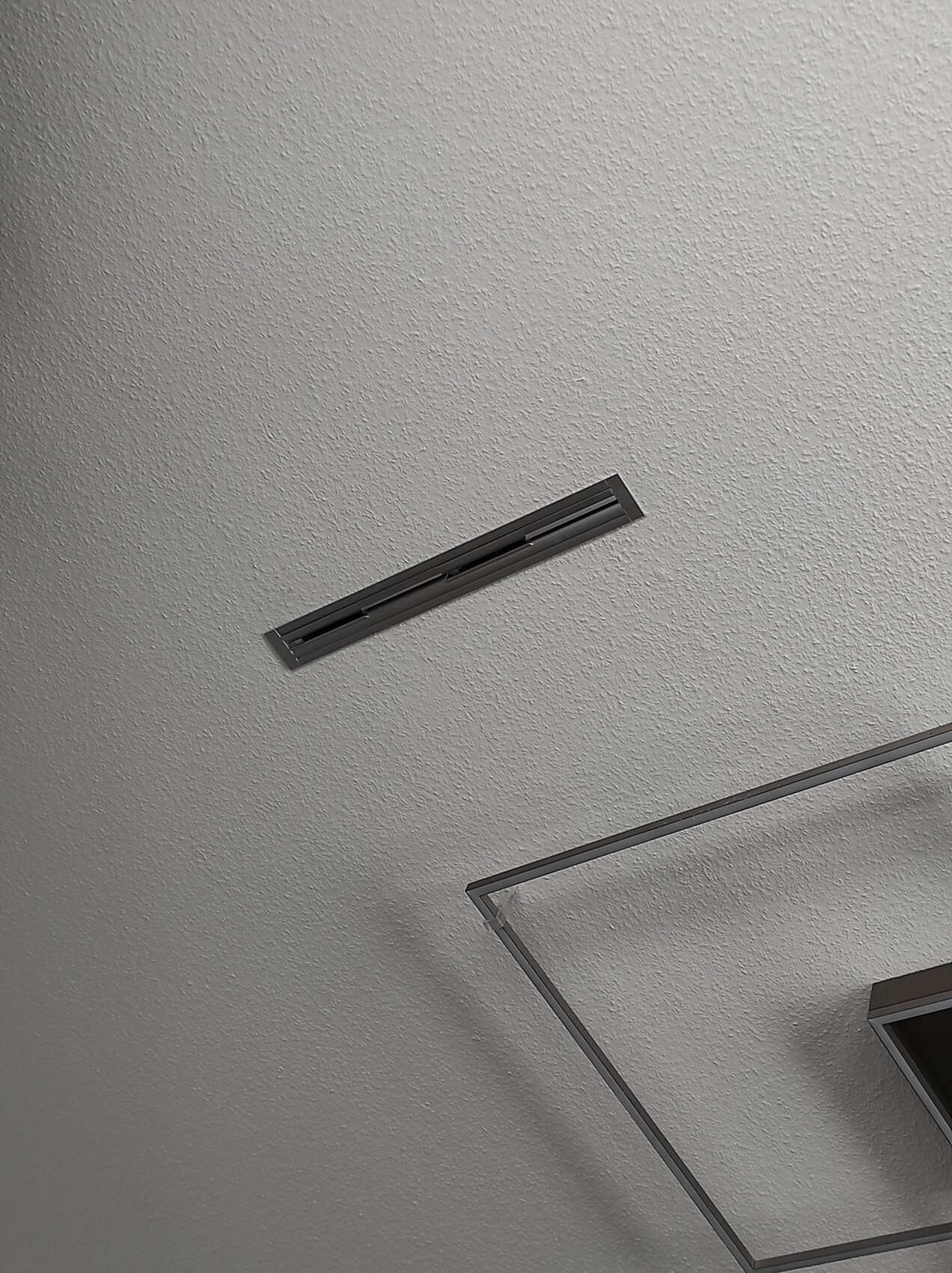 Moderne Decke mit rechteckigem Lüftungsgitter und Metallrahmen eines Lichtsystems