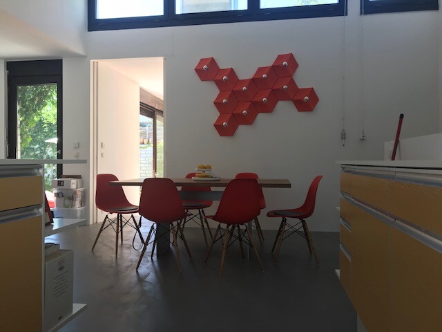 Moderne Essbereichszene mit roter Hexagon-Wanddekoration, Tisch und roten Stühlen.