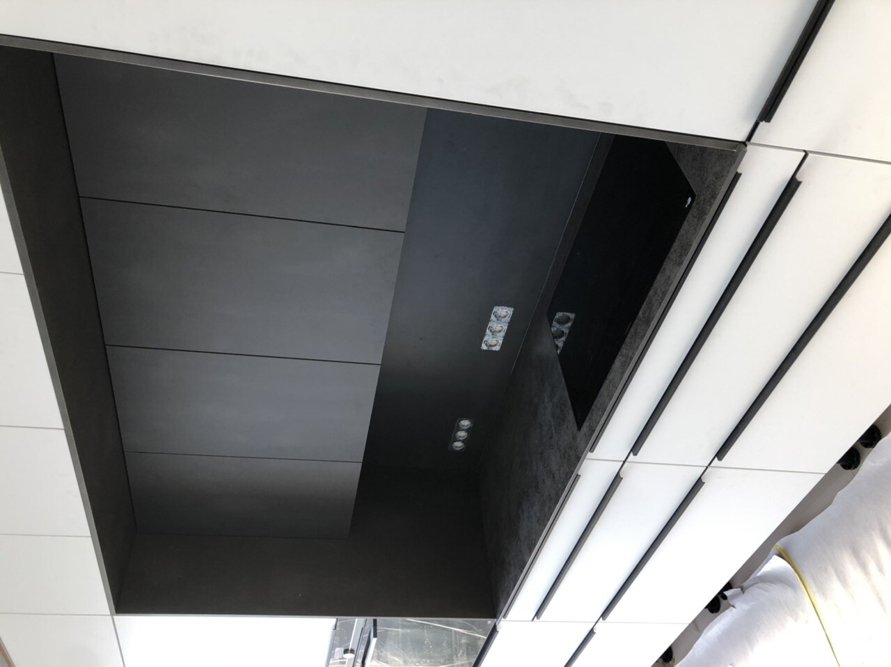 Moderne Küchenfront mit leerer, dunkler Einbau-Nische und LED-Spots, von hellen Fronten umgeben.