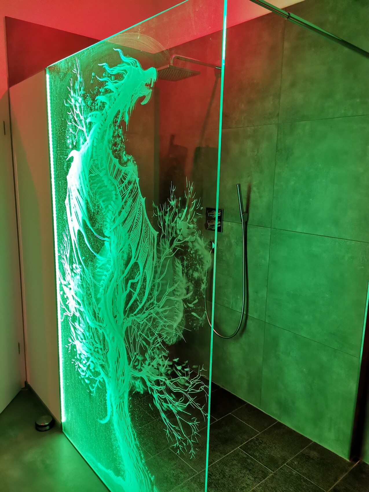 Glasdusche mit grüner Beleuchtung und großem gravierten Drachenmotiv auf dem Glas.
