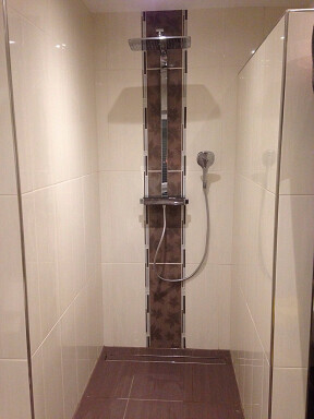 Duschbereich in modernem Badezimmer mit Glasabtrennung und Handbrause