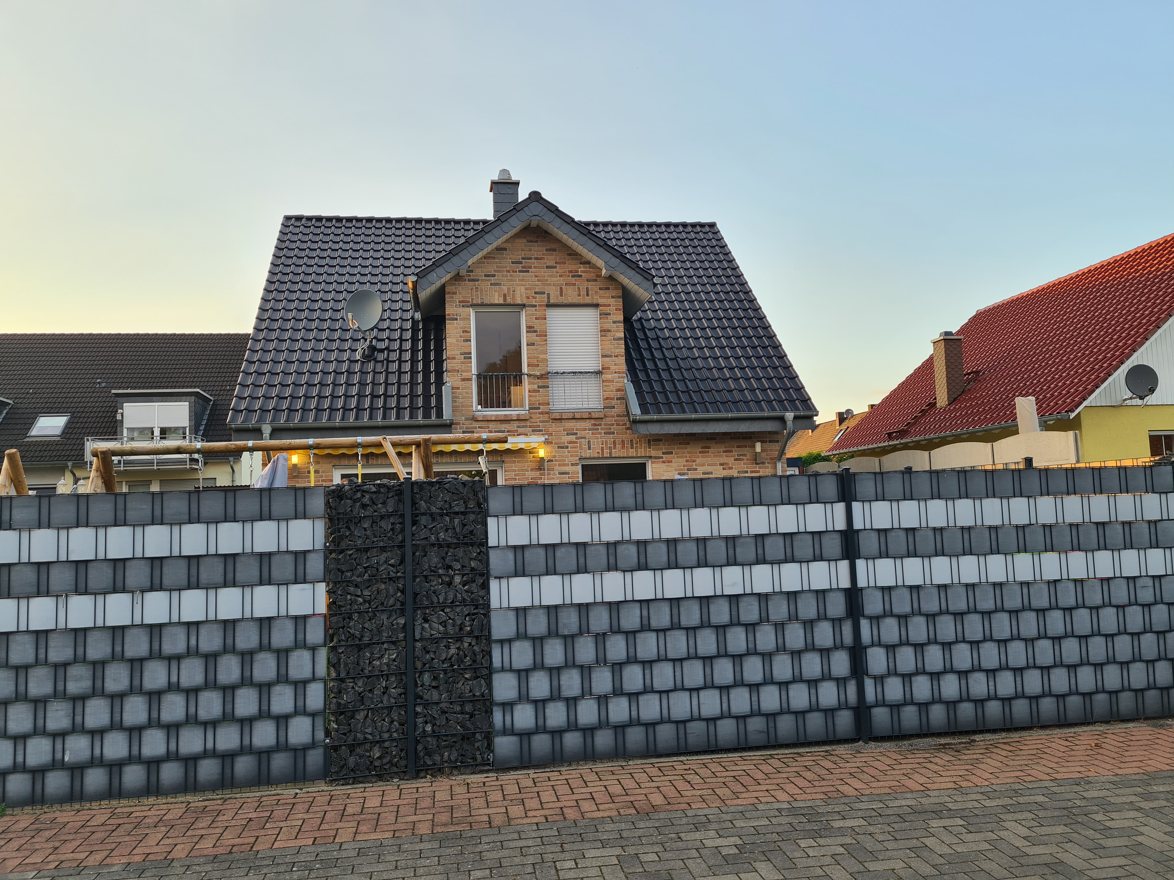 moderne-einfamilienhaus-aussenansicht-backstein-haus-dachziegeln-dunkle-fassade-zaun.jpg