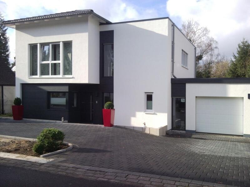 Moderne weiße Einfamilienhaus-Villa mit schwarzen Akzenten, großer Fensterfront und Garage.