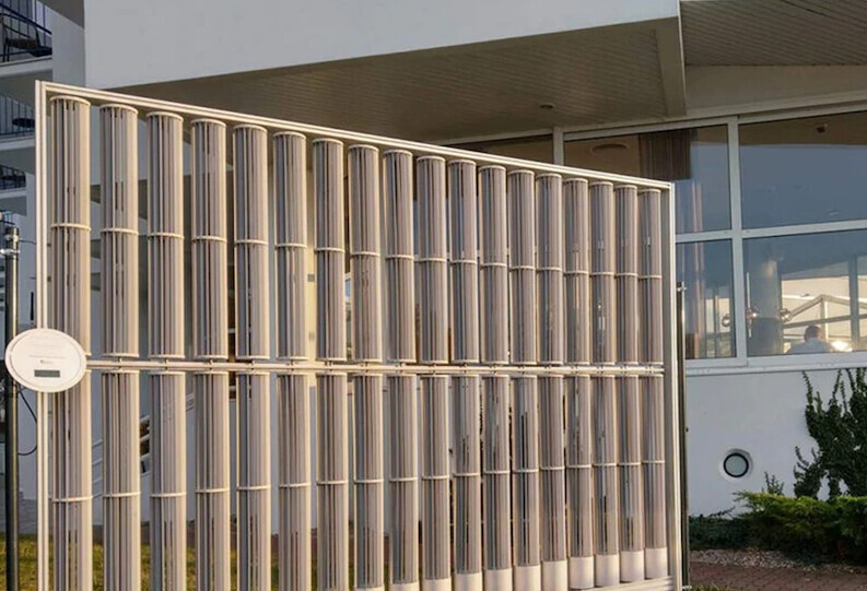 Modernes Bürogebäude hinter vertikalem Metallzaun mit Glasfenstern; runder Schild am Zaun