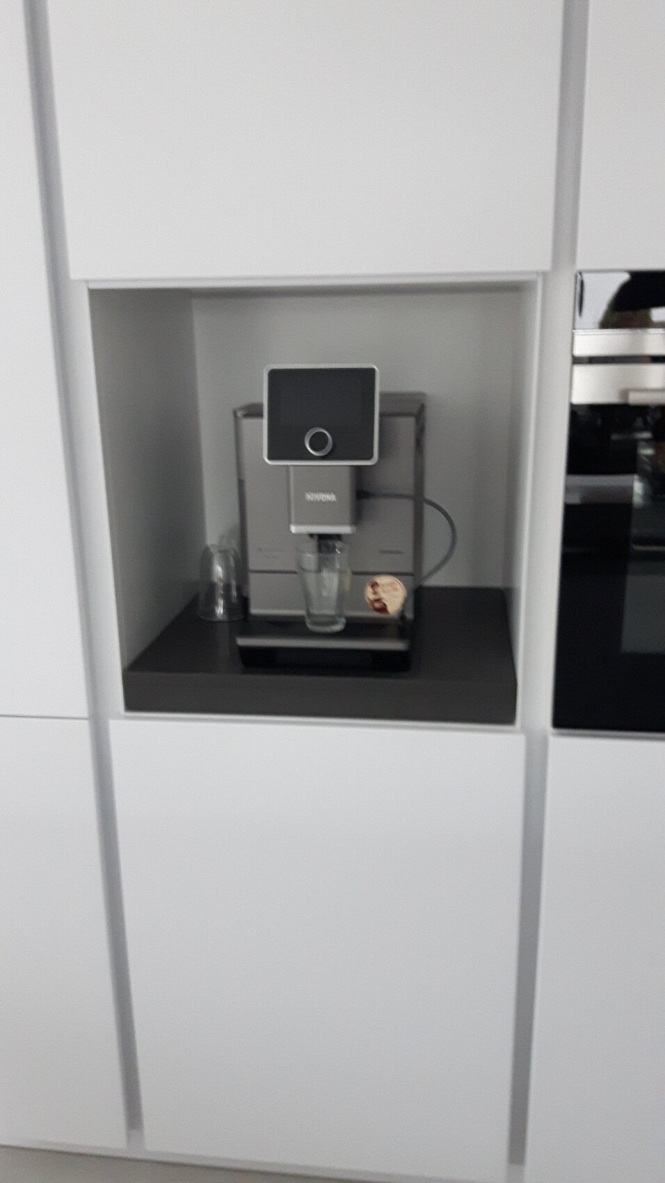 Kompakte NIVONA-Einbaukaffeemaschine in der Küche mit Glasbecher unter dem Auslauf