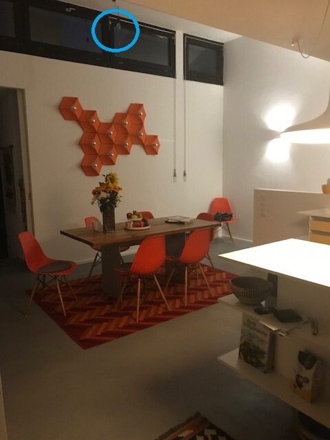 Esszimmer mit Holztisch, orange Stühle, Vase Sonnenblumen, geometrische orange Wanddeko und Teppich.