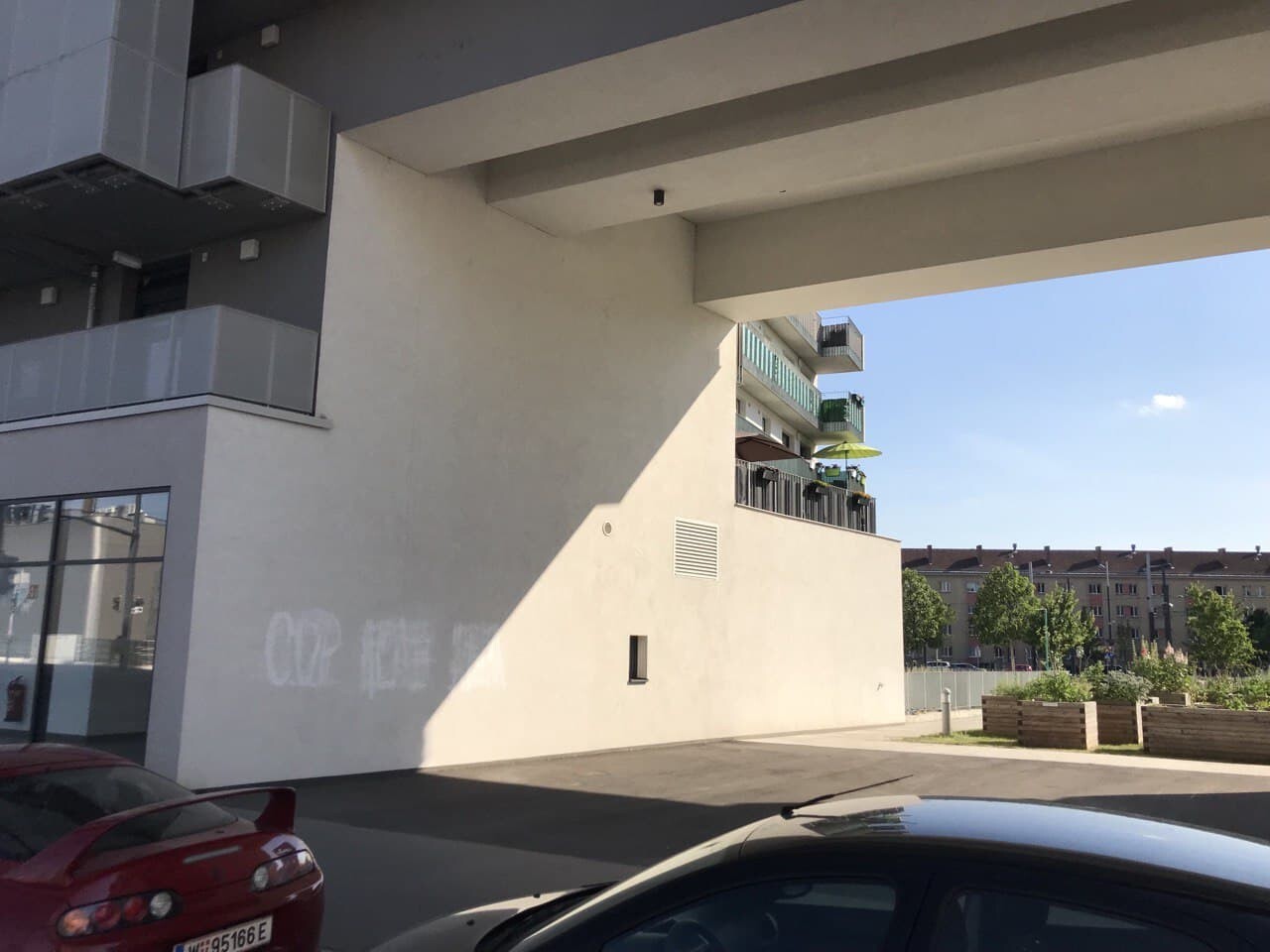 Moderne Gebäudefassade mit Unterführung, Parkplätzen und Gartenvorplatz im Außenbereich