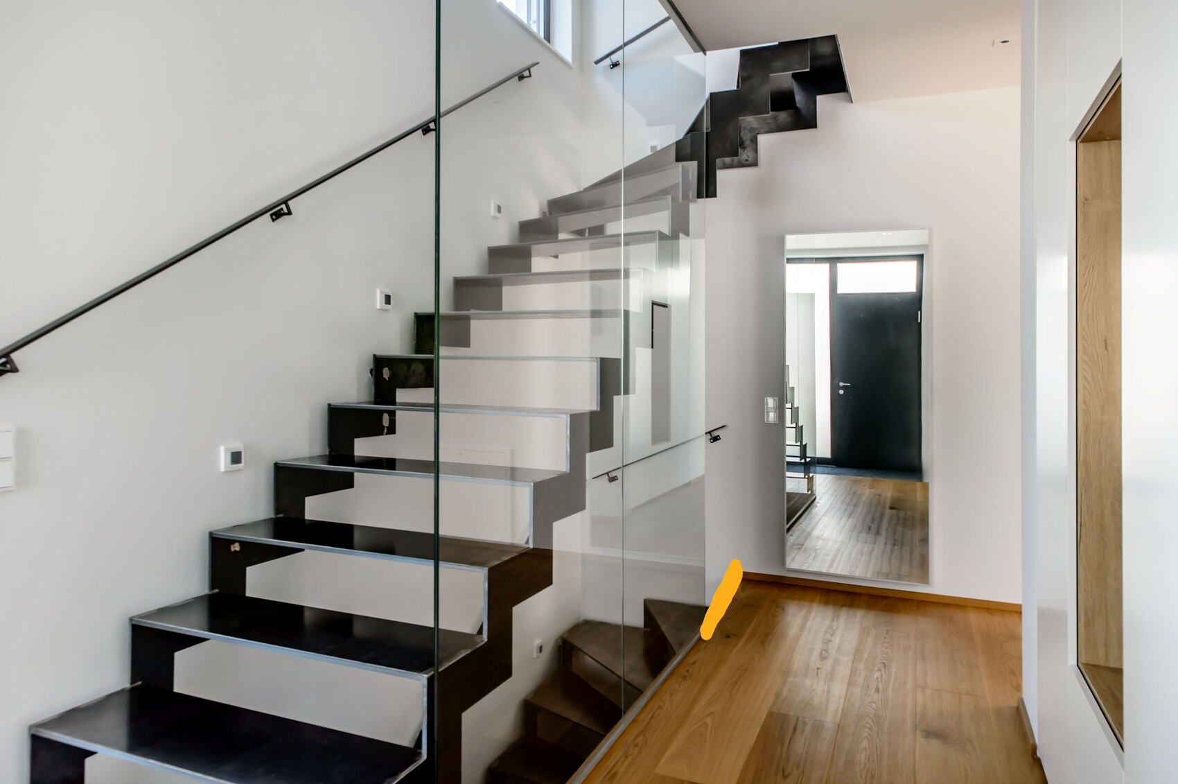 Moderne Eingangshalle mit offener schwebender Treppe, Glasgeländer, Spiegel und Holzboden