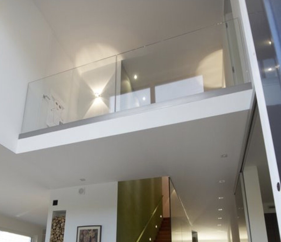 Heller Innenraum mit moderner Glasbalustrade am Mezzanin und Treppenaufgang.