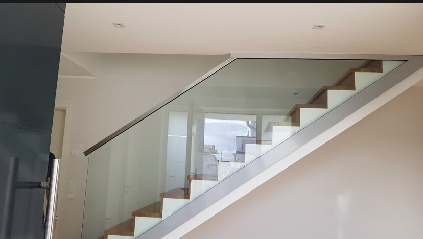 Moderne Innentreppe mit Glasgeländer und Holzstufen im hellen Innenraum