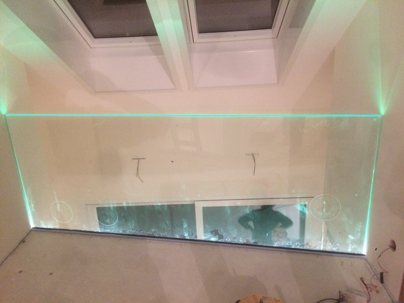 Transparente Glasfront mit grüner LED-Linie, Spiegelung einer Person, Oberlichter.