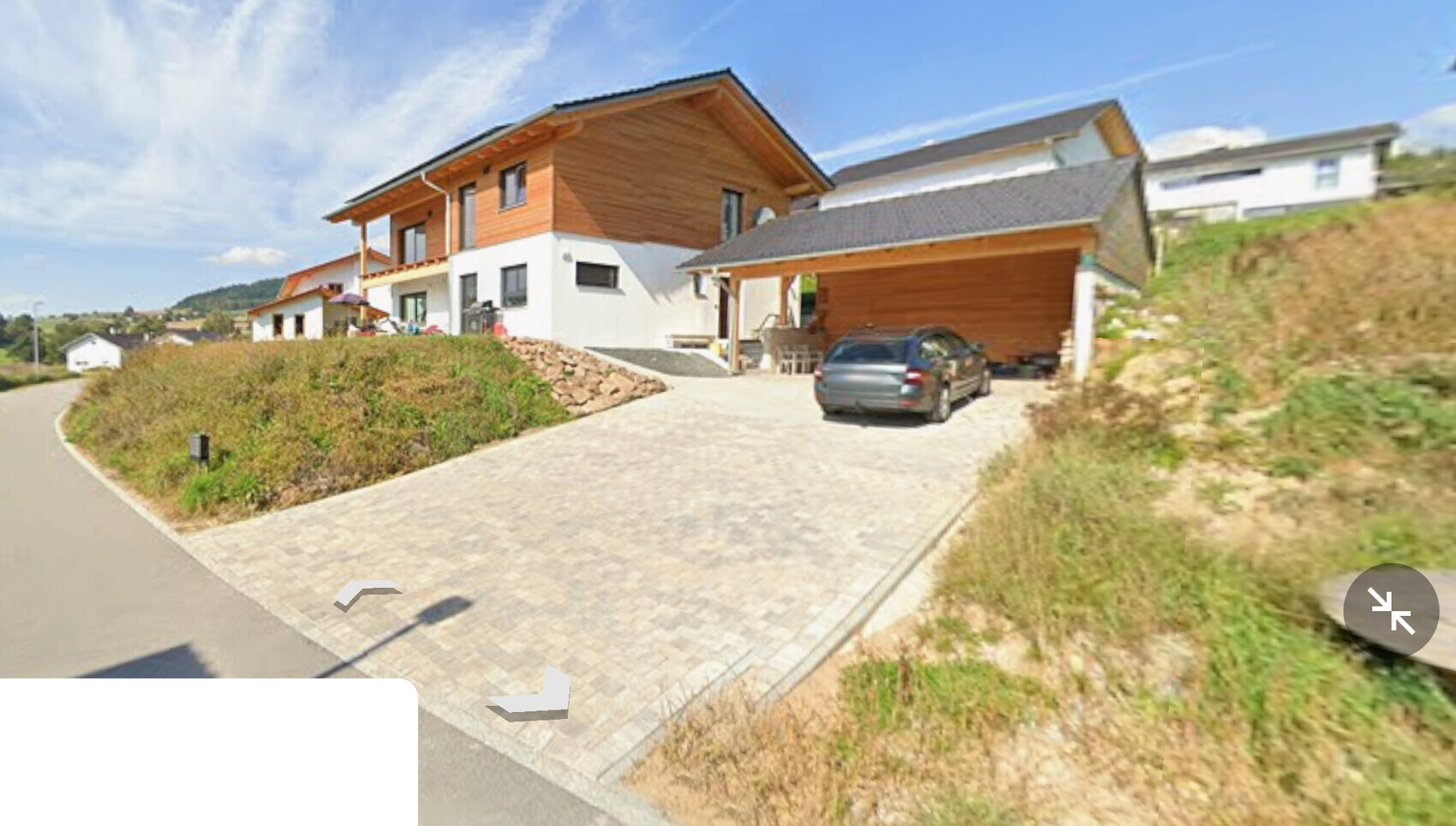 Modernes zweistöckiges Haus mit Holzfassade, Carport und gepflasterter Einfahrt