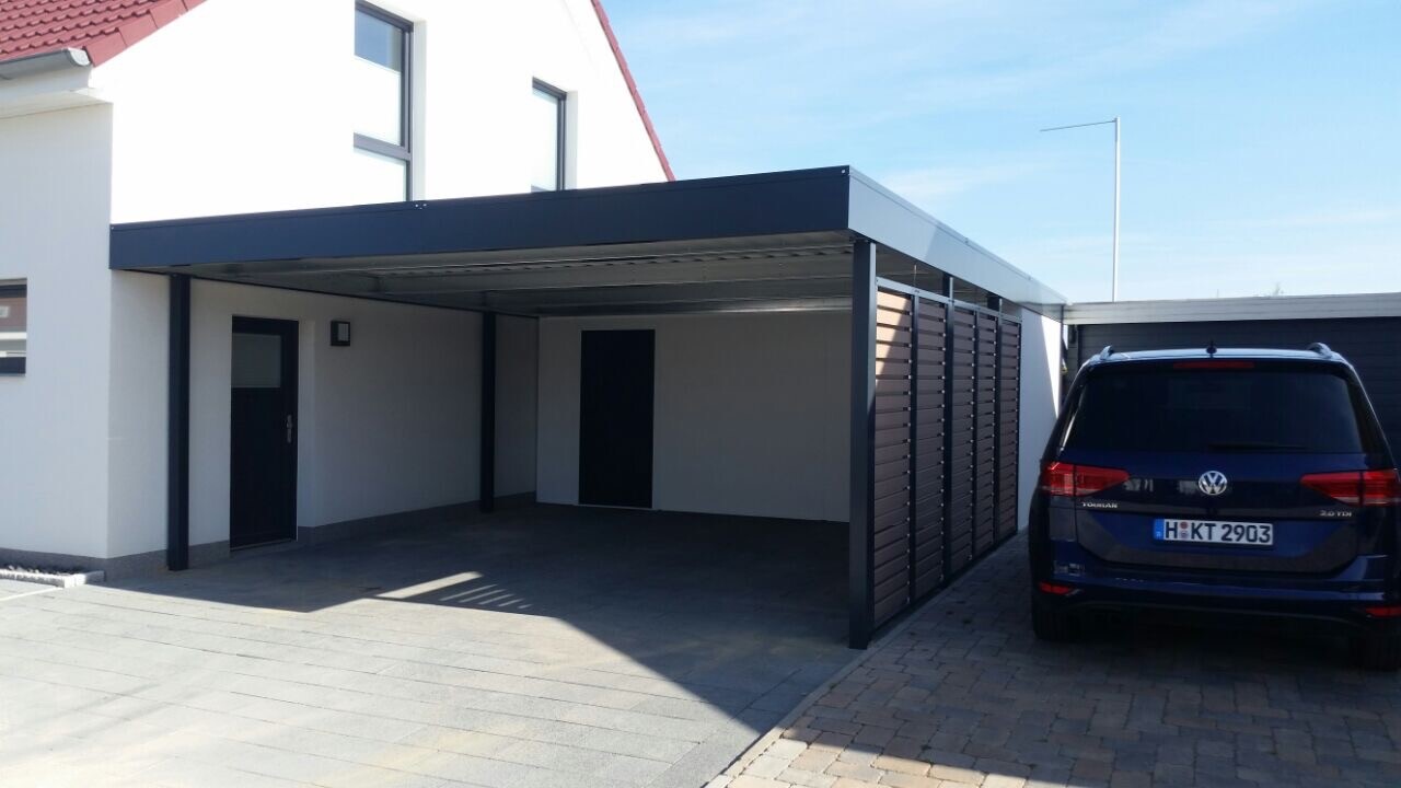 Moderne Carportanlage am weißen Haus; rechts geparkter dunkler VW Touran, Lamellenwand daneben.
