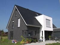 Modernes Haus mit dunkler Backsteinfassade und hellem Anbau, Außenansicht