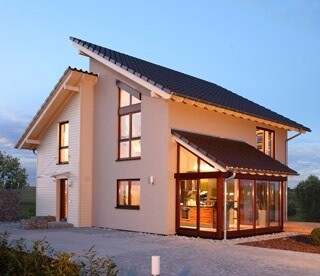 Zweistöckiges modernes Haus mit großem Wintergarten und beleuchteter Fassade im Abendlicht