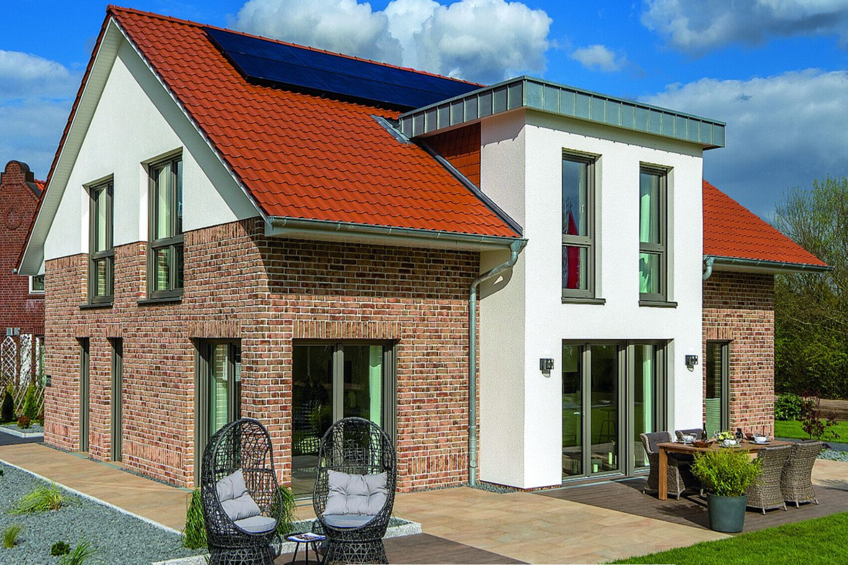 Modernes Haus außenansicht mit rotem Ziegeldach, Bruchsteinfassade und Terrasse.