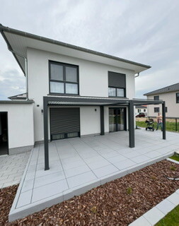 Moderne zweistoeckige Hausfront mit Terrasse und gepflastertem Vorplatz