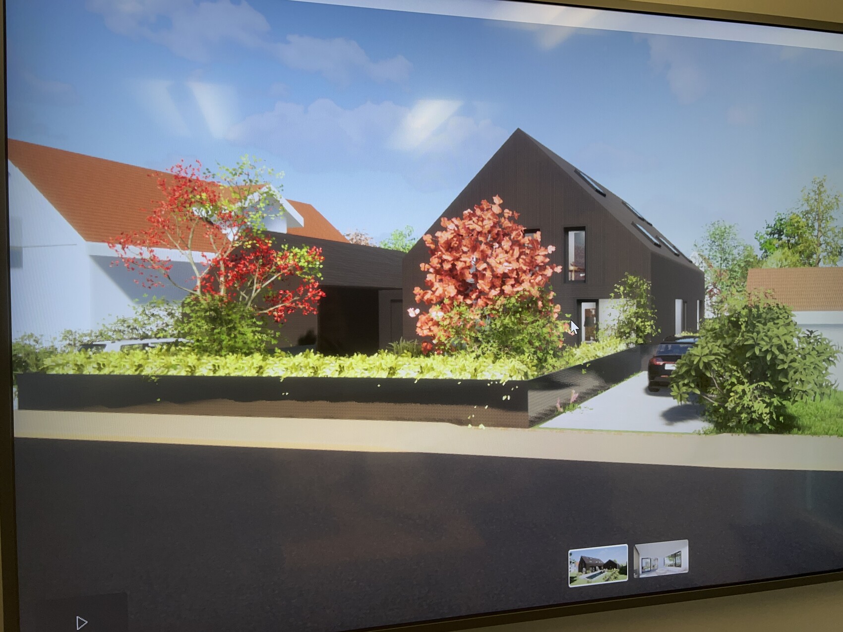 Moderne dunkle Hausfront mit Satteldach, roter Baum, Garten, geparktem Auto in der Einfahrt.