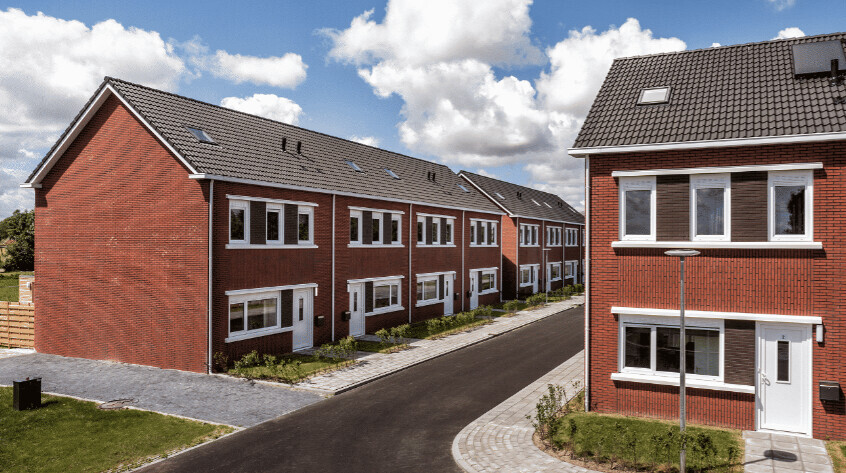 Reihenhaus-Siedlung aus roten Backsteinen, Straße, Gehwege und Wolkenhimmel