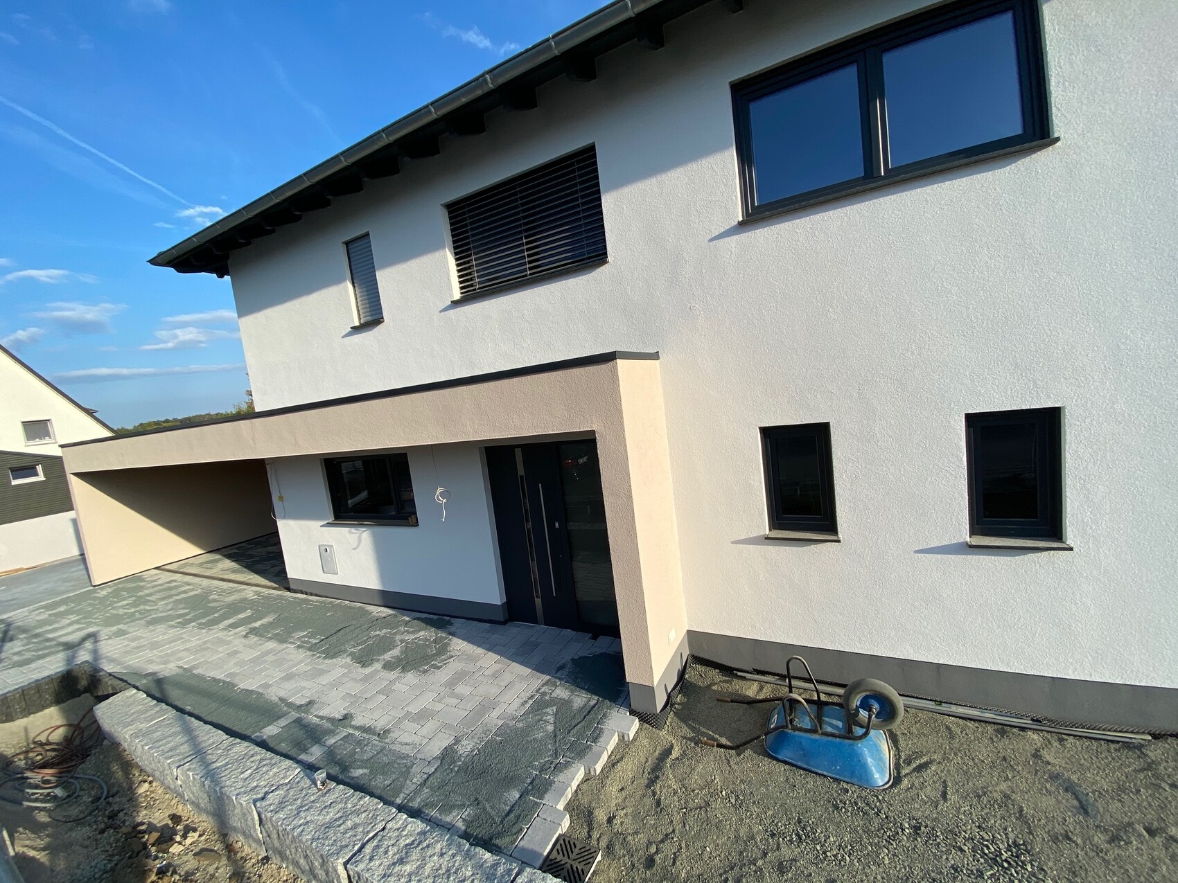 Moderne weiße zweistöckige Hausfassade mit Carport und großer Fensterfront