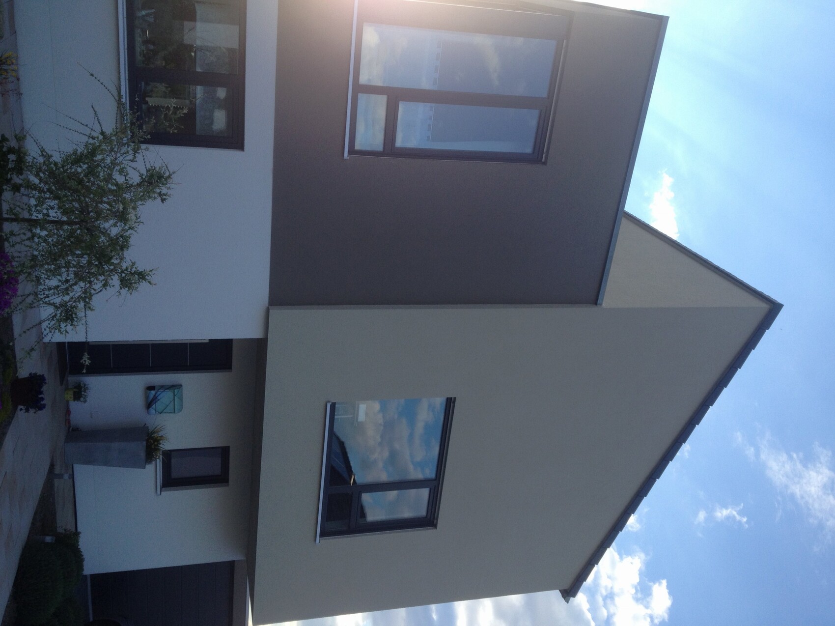 Moderne weisse Hausfassade mit grossen Fenstern und Eingangsbereich