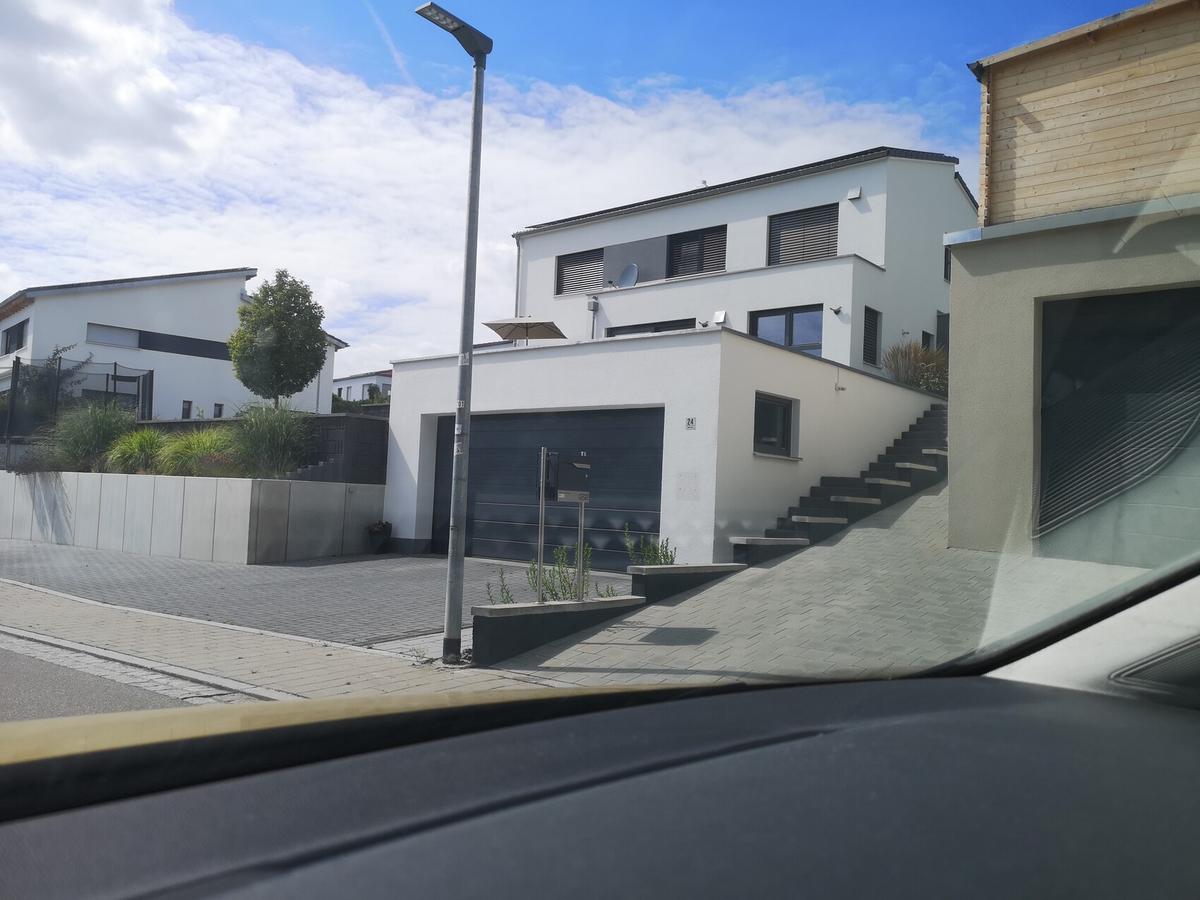 Moderne weiße Hausfassade mit Garage, Stufenaufgang und Zufahrt.