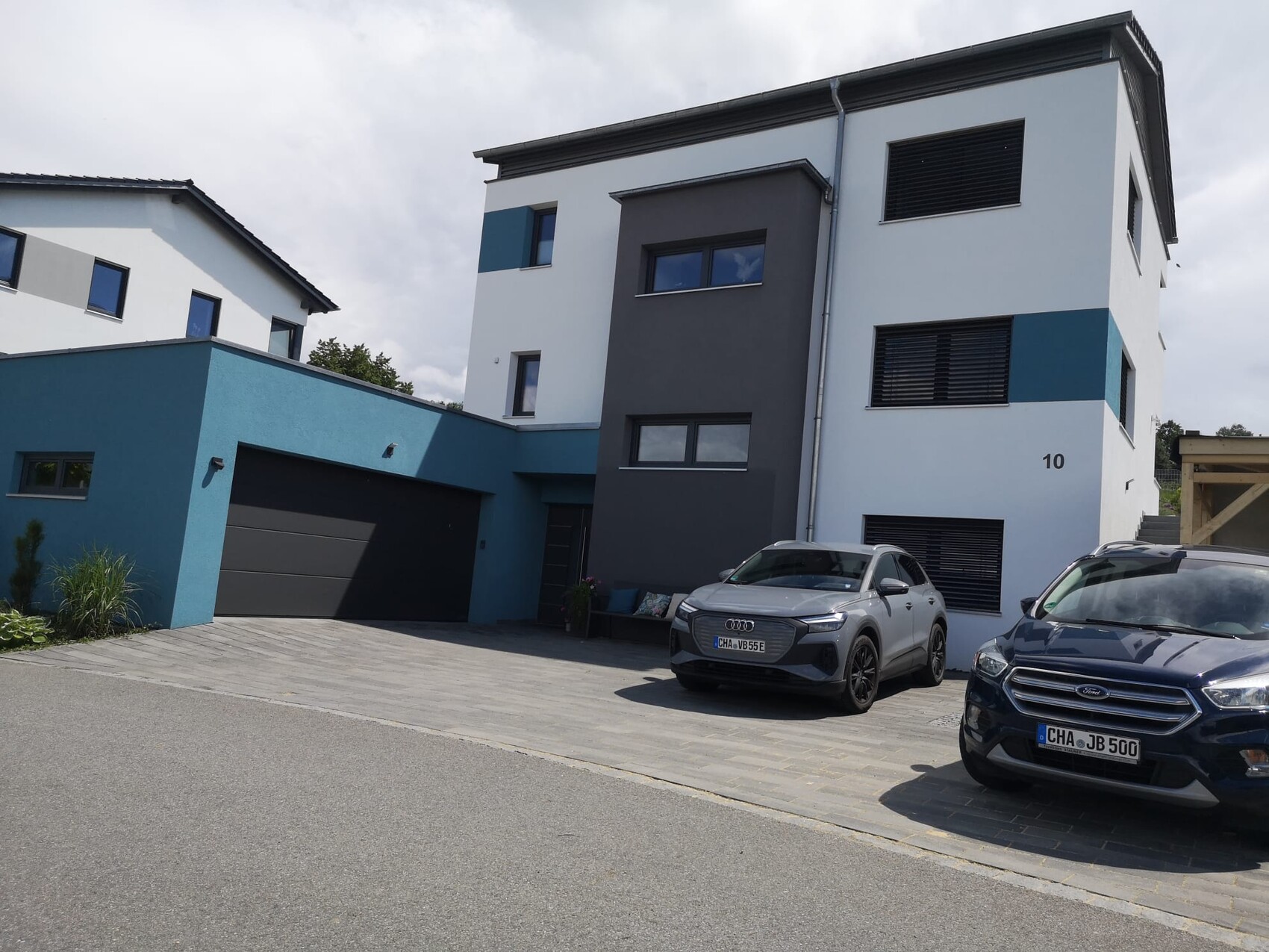 Moderne mehrstöckige Hausfassade mit Garage und zwei Autos davor