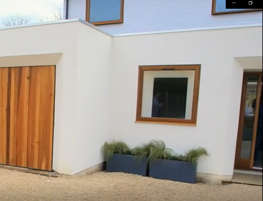 Moderne Häuserfassade: weiße Wand, Holzfenster, Holztüren, gläserne Tür, Pflanzkübel mit Gras