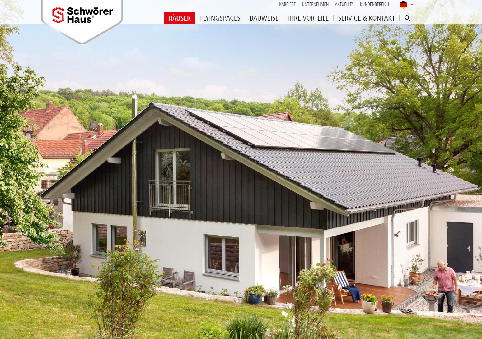 Modernes Einfamilienhaus mit Solar-Dachpaneelen, Terrasse und Garten im Grünen.