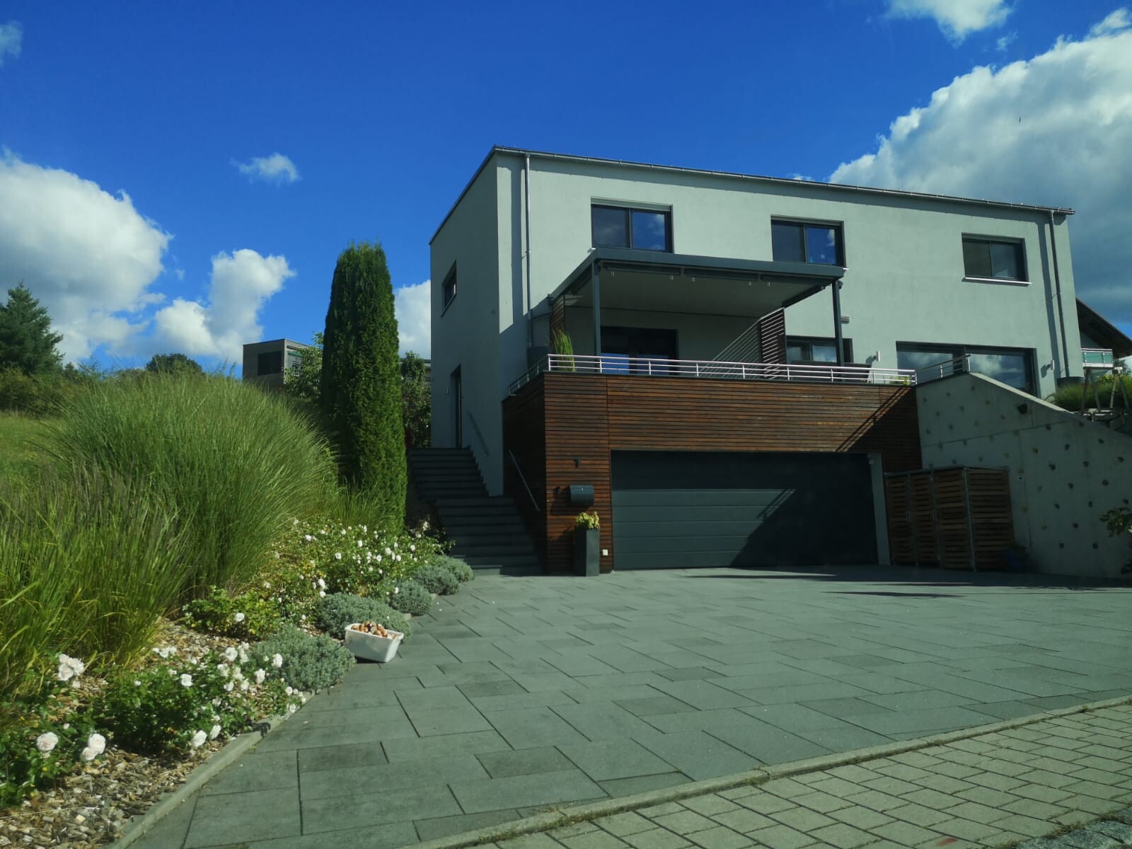 Moderne zweistöckige Hausfront mit Garage, Holzverkleidung und Vorgarten